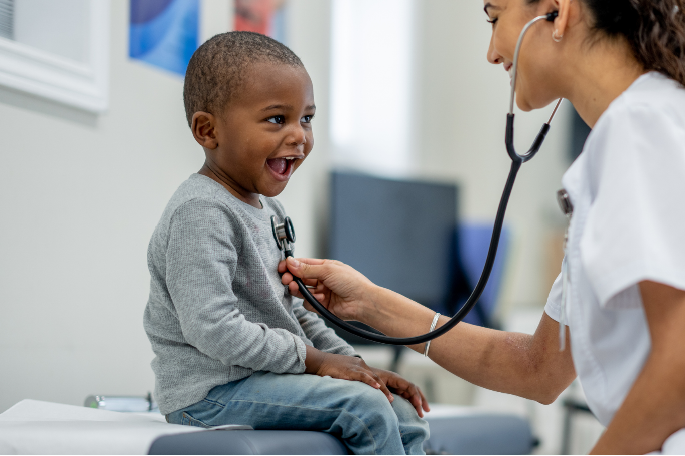Little boy smiling while a doctor examines his chest.