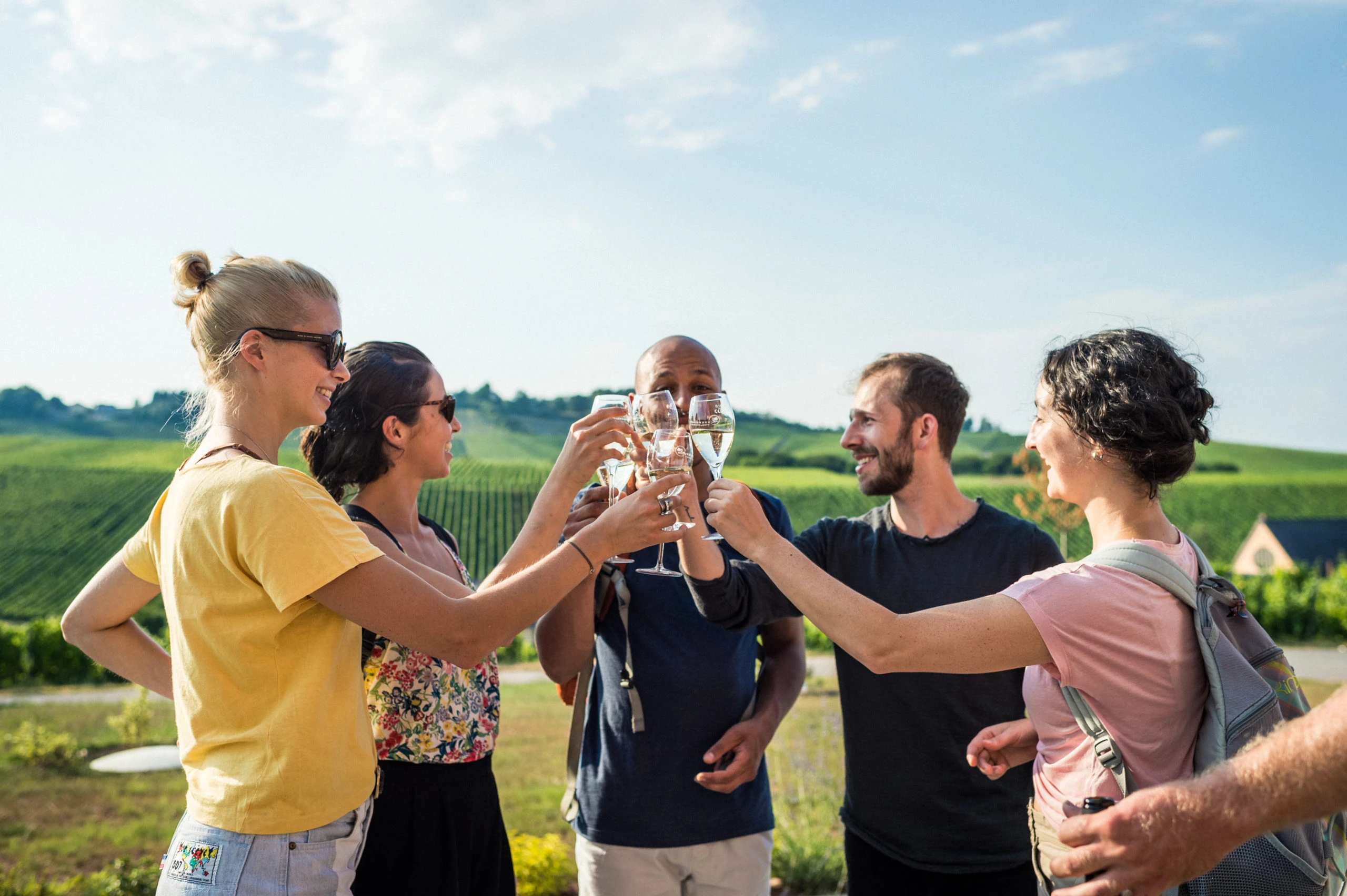 Group of five friends raising their glasses for a toast in Luxembourg’s Moselle wine region